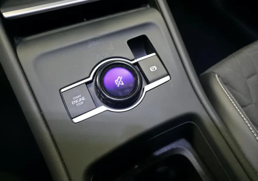 Gros plan sur la console centrale du Volkswagen Tiguan 2025, bouton rotatif violet et commandes de démarrage et frein à main.