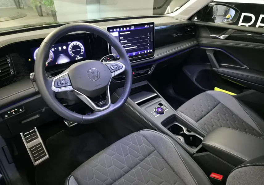 Vue intérieure côté conducteur du Volkswagen Tiguan 2025, tableau de bord numérique et écran tactile central visibles.
