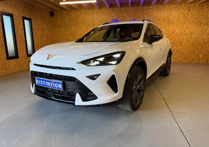 Vue 3/4 avant d'un CUPRA Formentor blanc avec détails noirs, calandre marquée et jantes foncées en intérieur bois.