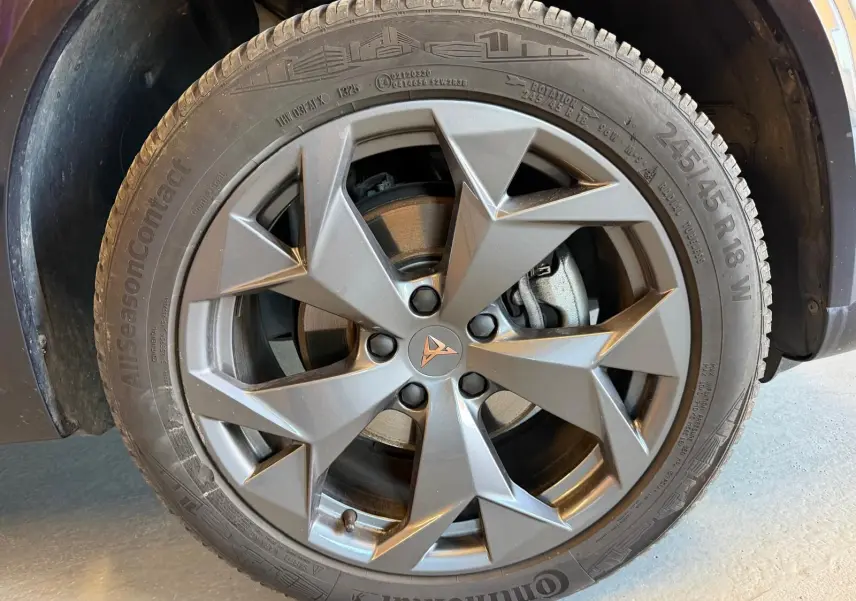 Gros plan sur la jante alliage gris anthracite avec logo CUPRA au centre, montée sur pneu Continental AllSeasonContact.