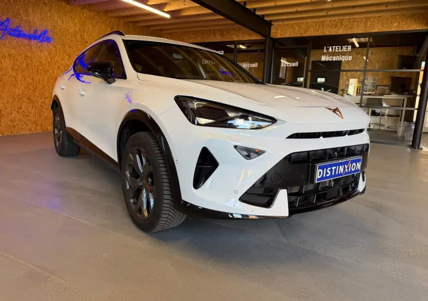 Vue 3/4 avant d'une CUPRA Formentor blanche avec détails noirs, calandre marquée et jantes foncées en showroom.