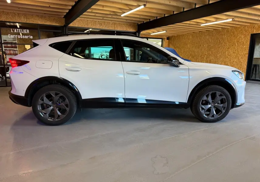 Profil côté gauche d’un CUPRA Formentor blanc 2025 avec jantes noires et entourage de vitres noir piano.