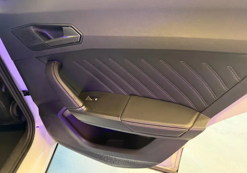 Vue rapprochée de la porte intérieure côté gauche du CUPRA Formentor blanc, avec surpiqûres apparentes et poignée en cuir.