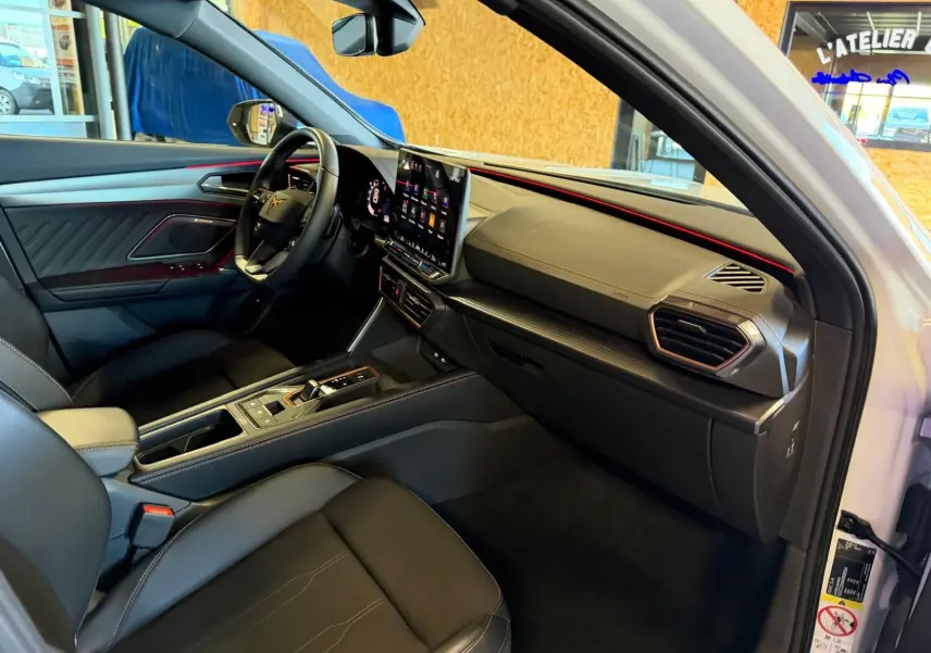 Intérieur avant droit du CUPRA Formentor blanc 2025, avec tableau de bord moderne et éclairage d'ambiance rouge.