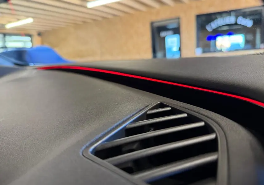 Gros plan sur la sortie d'air et la bande lumineuse rouge du tableau de bord du CUPRA Formentor blanc 2025.