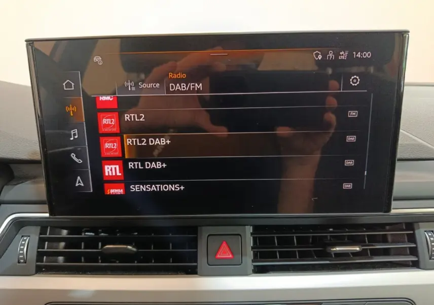 Écran tactile central de l’Audi A4 35 TFSI Business Line 2024 affichant les stations radio DAB/FM, intérieur noir.