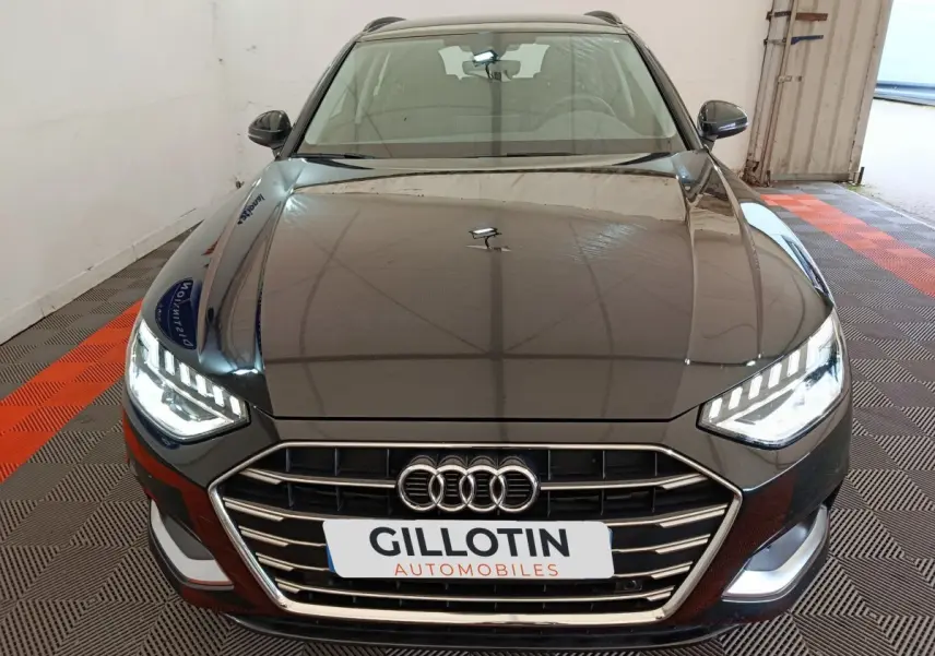 Vue avant d'une Audi A4 35 TFSI Business Line noire avec phares LED allumés dans un garage.