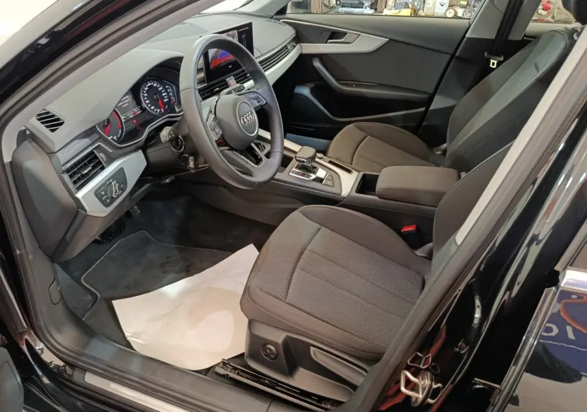 Vue intérieure côté conducteur de l'Audi A4 35 TFSI 2024 noire, avec tableau de bord numérique et sièges tissu gris.