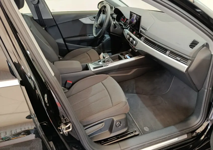 Vue intérieure côté conducteur de l'Audi A4 35 TFSI Business Line noire, avec tableau de bord moderne et sièges tissu gris.