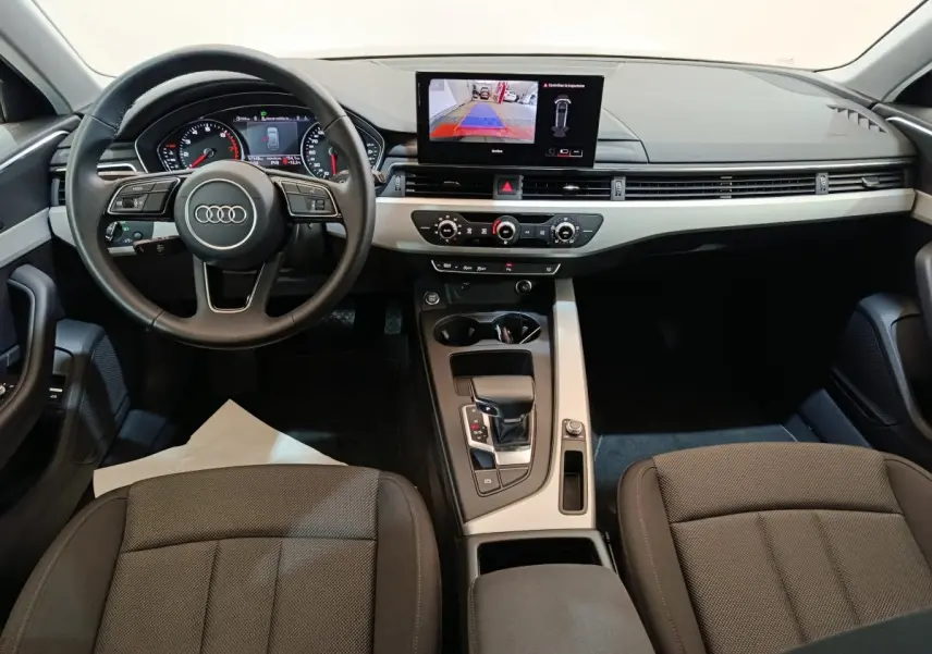 Vue intérieure avant de l'Audi A4 35 TFSI Business Line 2024, tableau de bord noir avec écran central tactile et volant cuir multifonctions.