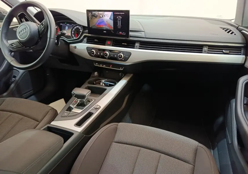 Intérieur Audi A4 35 TFSI 2024 vu côté conducteur, tableau de bord moderne avec écran central et volant cuir noir.