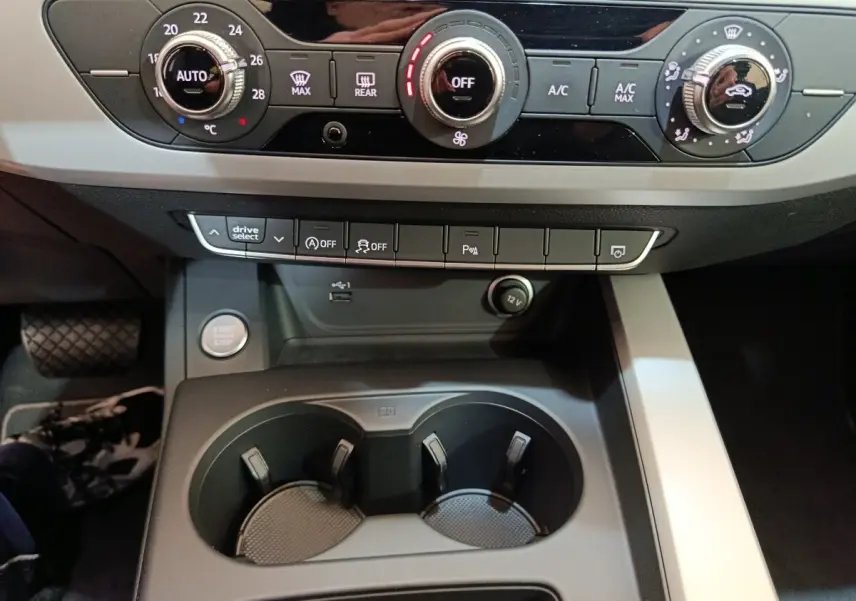 Vue rapprochée du tableau de bord et console centrale noire de l'Audi A4 35 TFSI 2024 avec commandes climatisation et boutons fonctionnels.