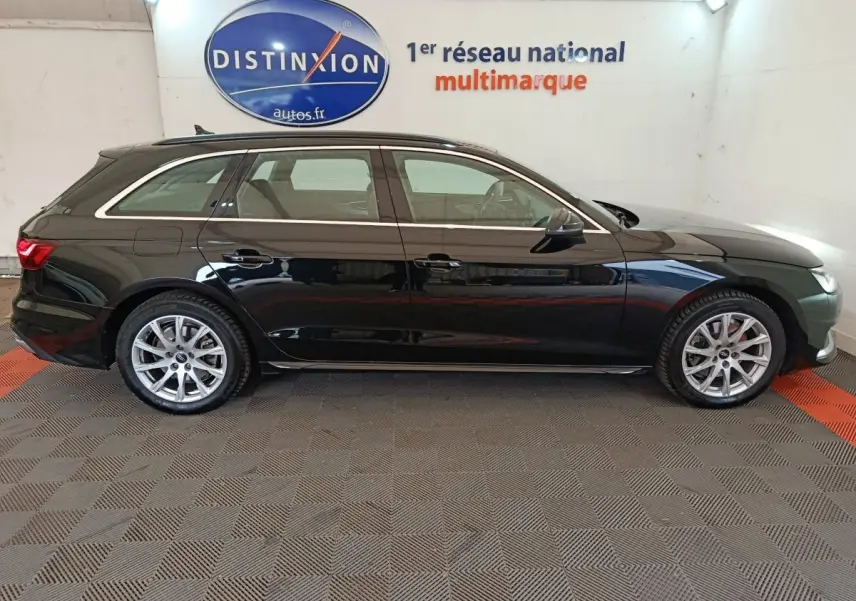 Audi A4 35 TFSI Business Line noire vue de profil côté droit dans un showroom avec logo Distinxion en arrière-plan.