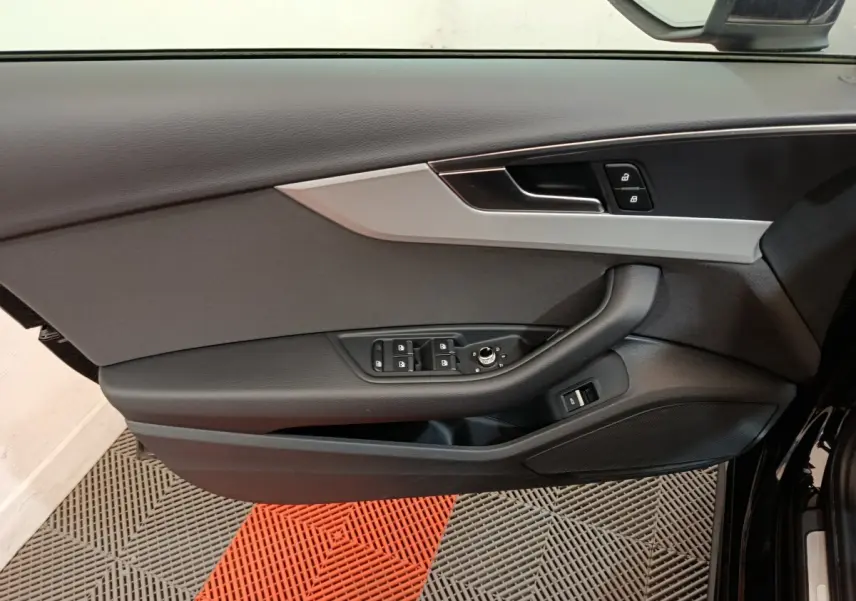 Vue intérieure côté gauche de la porte avant noire d'Audi A4 2024, avec commandes de vitres et verrouillage.