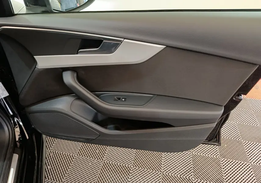 Vue rapprochée de la porte avant gauche noire de l'Audi A4 35 TFSI 2024 avec garniture grise et commande de vitre.