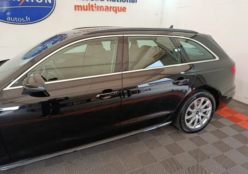 Vue latérale droite d'une Audi A4 noire 2024 break, mettant en valeur ses jantes alliage et ses vitres teintées.