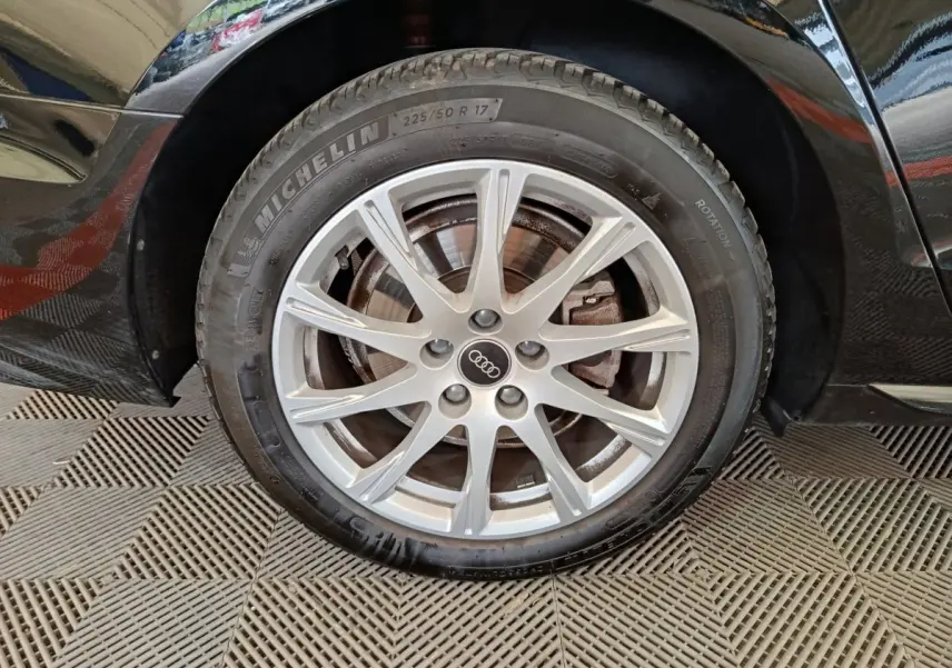 Gros plan sur la roue avant droite noire d'une Audi A4 35 TFSI 150 S tronic Business Line avec jante alliage argentée.