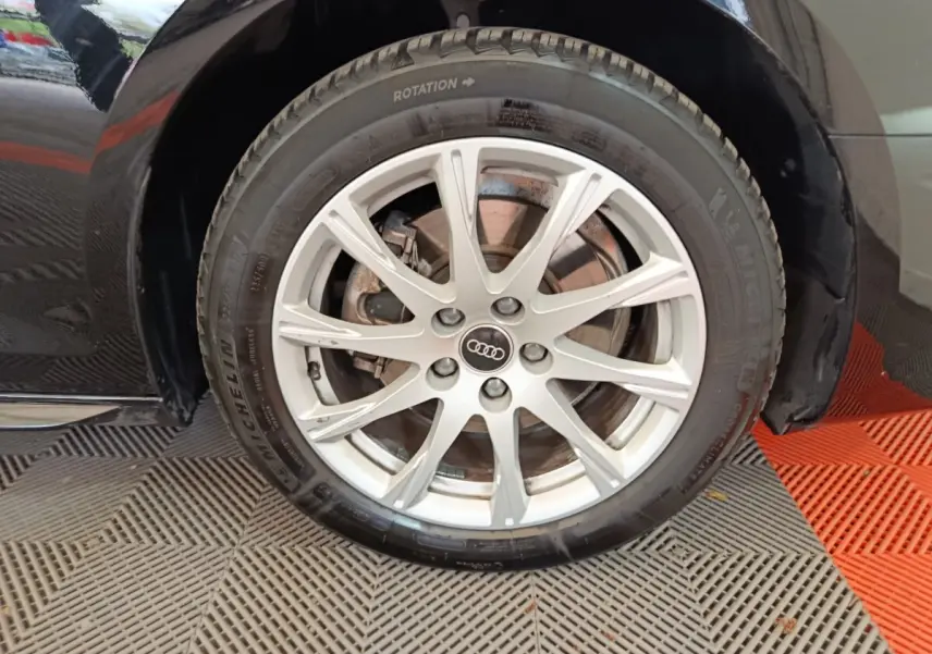 Gros plan sur la roue avant droite noire d'une Audi A4 35 TFSI 150 S tronic Business Line avec jante argentée multi-branches.
