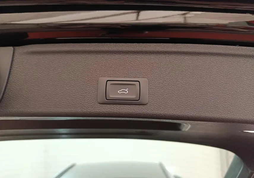 Bouton d'ouverture électrique du coffre sur la partie intérieure du hayon noir d'une Audi A4 35 TFSI 2024.