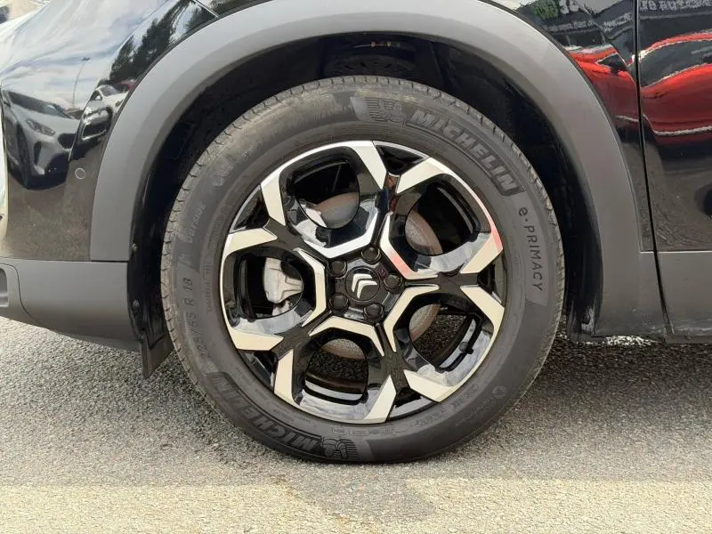 Gros plan sur la roue avant gauche noire et argentée du Citroën C5 Aircross 1.2 Hybride 2024 Noir Perla Nera.