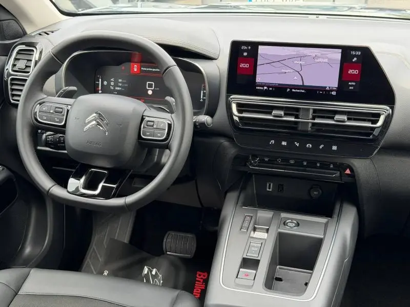 Intérieur du Citroën C5 Aircross 2024 noir, vue du poste de conduite avec volant multifonction et écran tactile GPS.