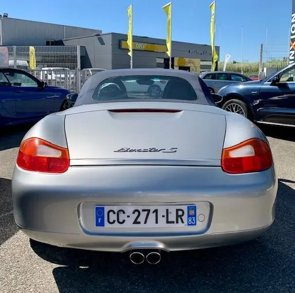Vue arrière d'une Porsche Boxster S 986 gris 2001 avec capote grise et double sortie d'échappement centrale.