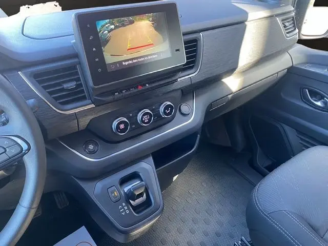 Intérieur du Renault Trafic cabine approfondie 2025, tableau de bord avec écran caméra de recul et commandes climatisation.