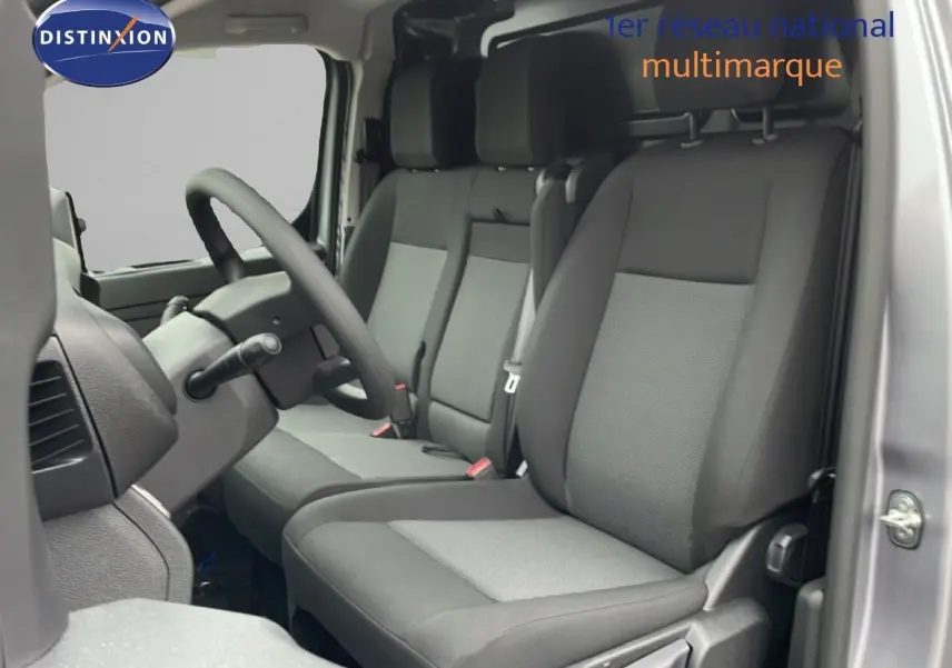 Vue intérieure côté conducteur du Citroën Jumpy gris Artense, montrant les sièges tissu bicolore et le volant multifonction.