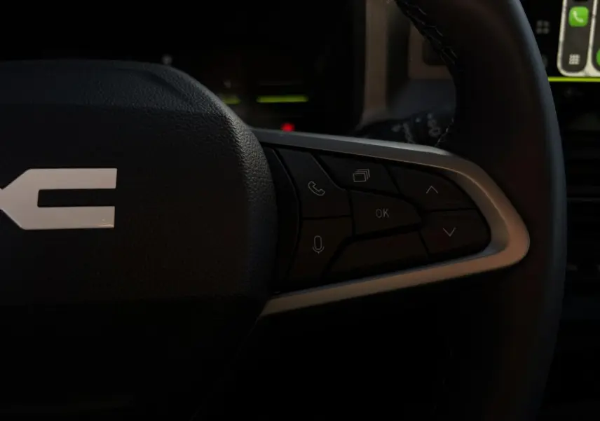 Gros plan sur les commandes multifonctions côté droit du volant du Dacia Duster 2026, intérieur noir.