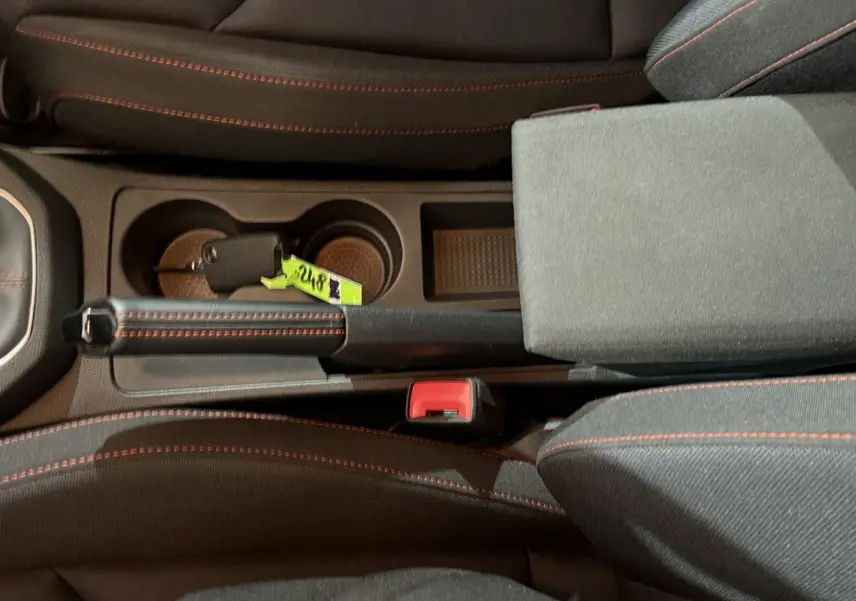 Vue plongeante sur la console centrale noire de la SEAT IBIZA 1.0 TSI 110 FR avec frein à main et clé posée.