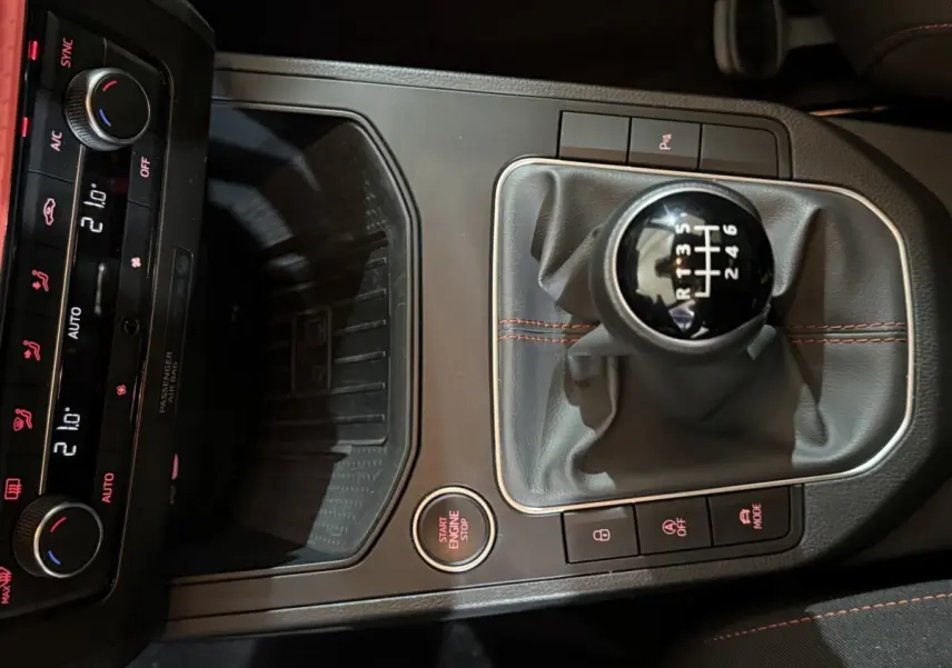 Vue rapprochée de la console centrale noire de la SEAT Ibiza 1.0 TSI 110 FR 2024, avec levier de vitesses manuel et commandes éclairées.