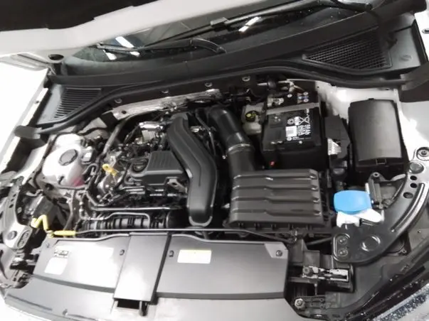 Vue plongeante sur le moteur essence du Volkswagen T-Roc blanc toit noir, montrant le compartiment moteur bien organisé.