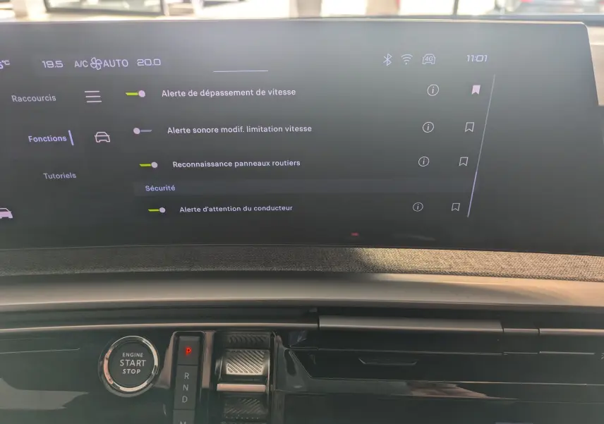 Vue rapprochée de l’écran tactile et console centrale du Peugeot 5008 hybride 2025, avec bouton start/stop et commandes de boîte auto.