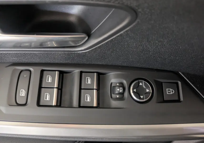 Gros plan sur les commandes de lève-vitres et rétroviseurs côté conducteur du Peugeot 5008 gris titane 2025.