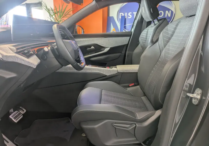 Vue intérieure côté conducteur du Peugeot 5008 hybride gris titane, sièges tissu/tep avec surpiqûres Iced Clay et tableau de bord moderne.