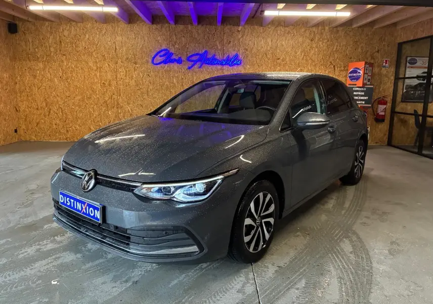 Volkswagen Golf 1.5 eTSI gris vue 3/4 avant droit dans un garage avec éclairage intérieur.