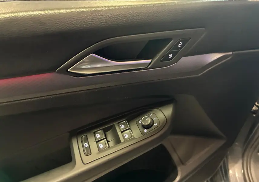 Détail de la porte côté conducteur d’une Volkswagen Golf gris 2022, avec commandes électriques des vitres et verrouillage.