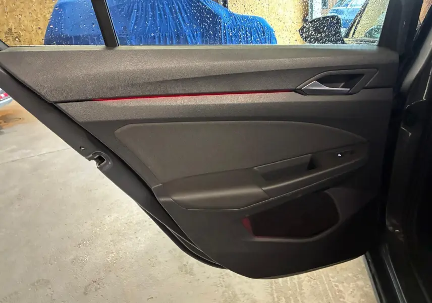 Vue intérieure de la porte arrière droite grise de la Volkswagen Golf 1.5 eTSI 130 DSG7 Active avec bande lumineuse rouge.