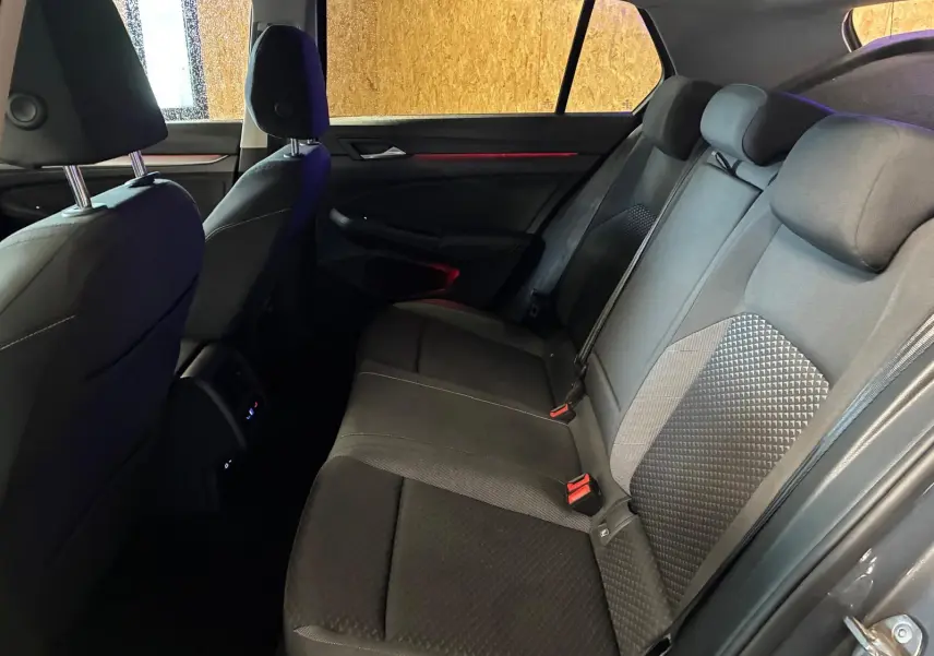 Vue intérieure arrière côté droit de la Volkswagen Golf gris, montrant les sièges arrière en tissu noir avec détails texturés.