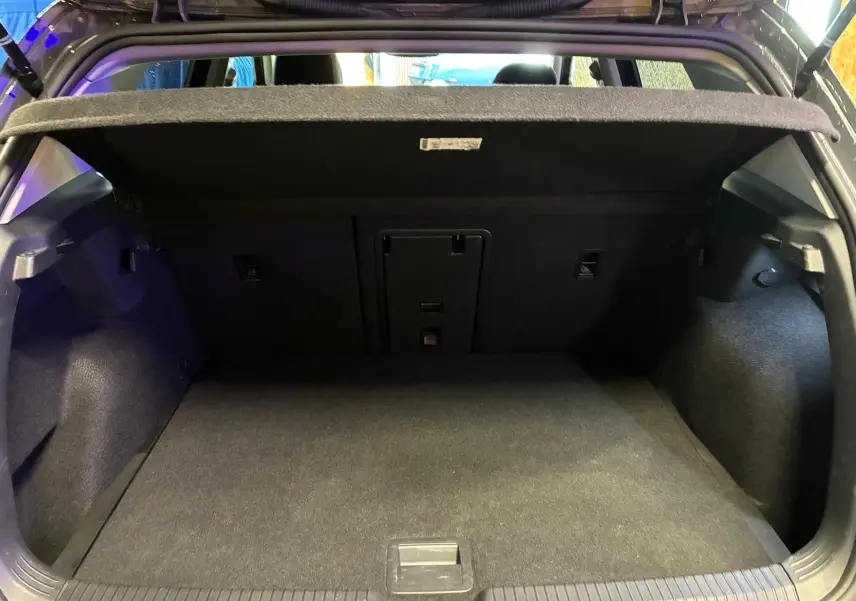 Coffre ouvert vu de l'arrière d'une Volkswagen Golf 1.5 eTSI 130 DSG7 Active, intérieur noir et tapis de coffre gris foncé.