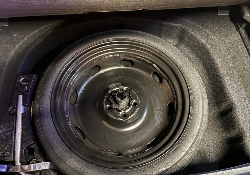 Vue en plongée sur la roue de secours noire logée dans le coffre d'une Volkswagen Golf gris 2022.