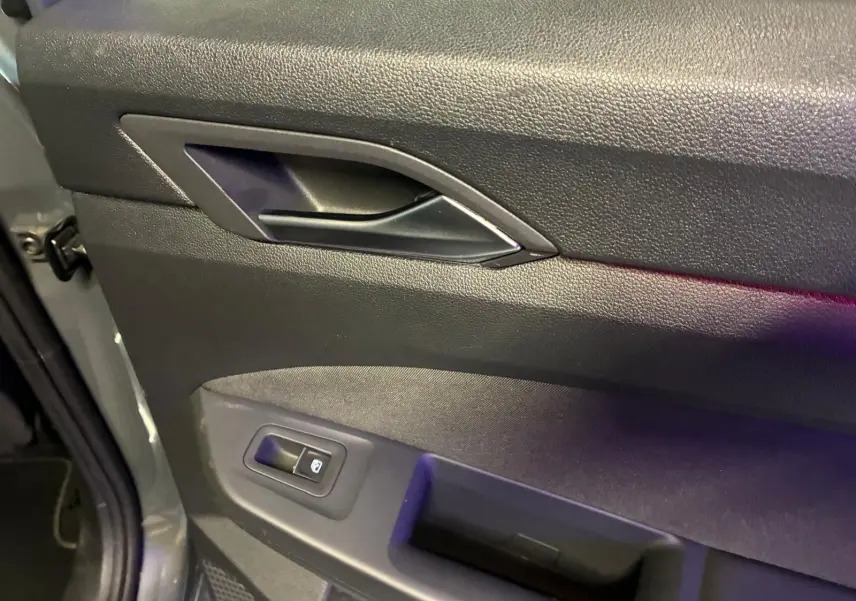 Gros plan sur la porte intérieure côté conducteur d'une Volkswagen Golf gris 1.5 eTSI 130 DSG7 avec bouton de verrouillage.