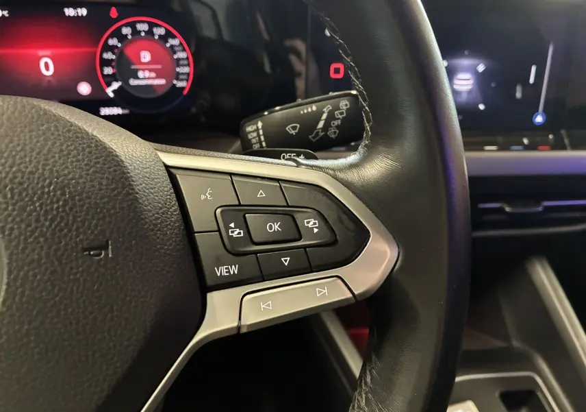 Gros plan sur le volant noir avec commandes multifonctions et tableau de bord numérique rouge d'une Volkswagen Golf 1.5 eTSI 130 DSG7 Active 2022.