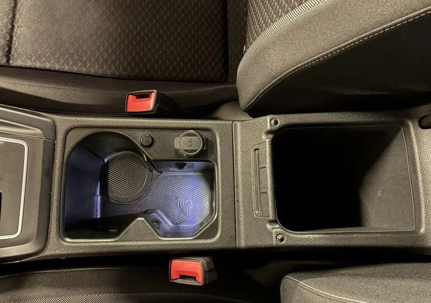 Vue plongeante sur la console centrale intérieure grise de la Volkswagen Golf 1.5 eTSI 130 DSG7 avec porte-gobelets et prise 12V.