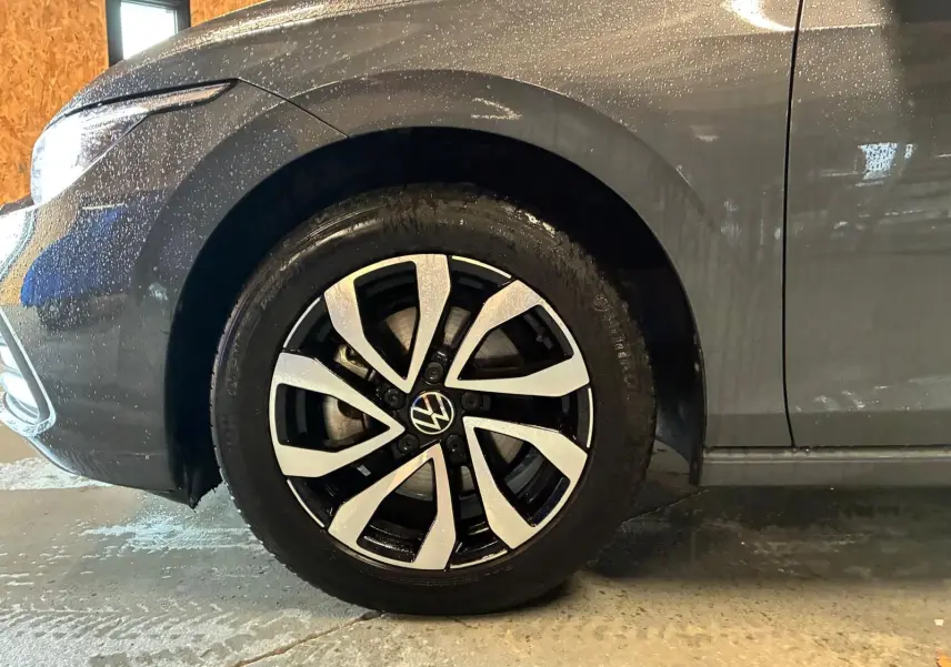 Gros plan sur la roue avant gauche d'une Volkswagen Golf 1.5 eTSI 130 gris 2022 avec jante alliage bicolore.