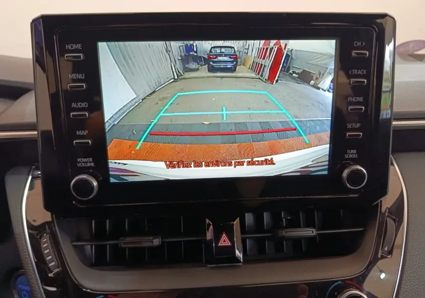 Vue de l'écran central de la Toyota Corolla Hybride blanche 2020 montrant la caméra de recul avec repères colorés.