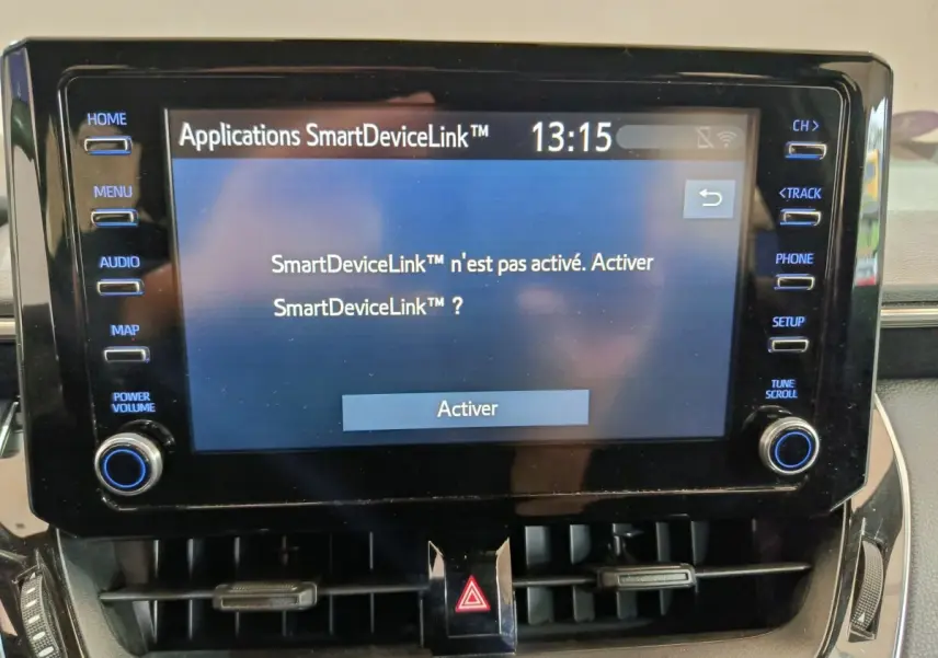 Gros plan sur l'écran tactile central noir de la Toyota Corolla Hybride 122h Active affichant le menu SmartDeviceLink à activer.