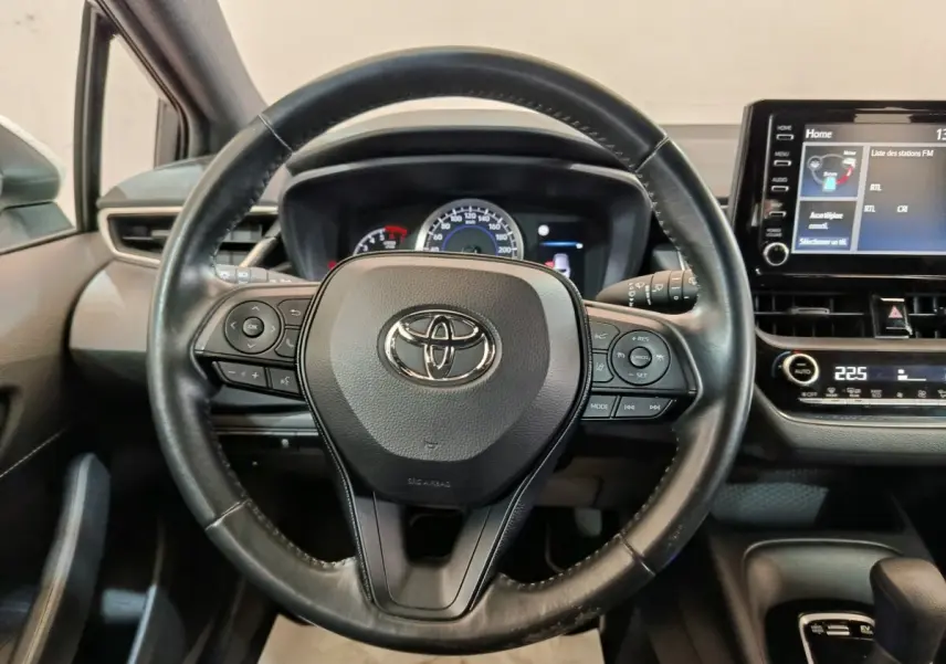 Vue rapprochée du volant cuir noir de la Toyota Corolla Hybride 122h 2020 avec tableau de bord et écran tactile visible.