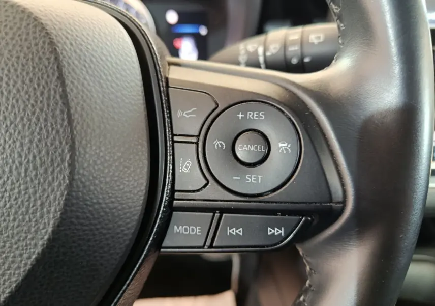 Gros plan sur les commandes multifonctions à droite du volant cuir noir de la Toyota Corolla Hybride 122h Active.