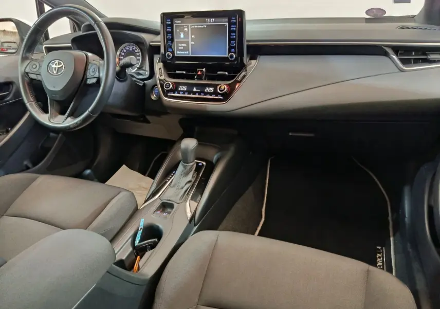 Intérieur de la Toyota Corolla Hybride 122h 2020 vu côté conducteur, tableau de bord noir avec écran tactile central et console centrale.